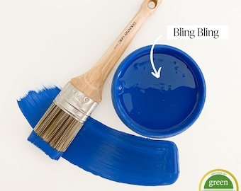 May include: A blue paint in a small container with a wooden paint brush and a paint stroke. The paint is labeled "Bling Bling" and has a greenwise gold certification.