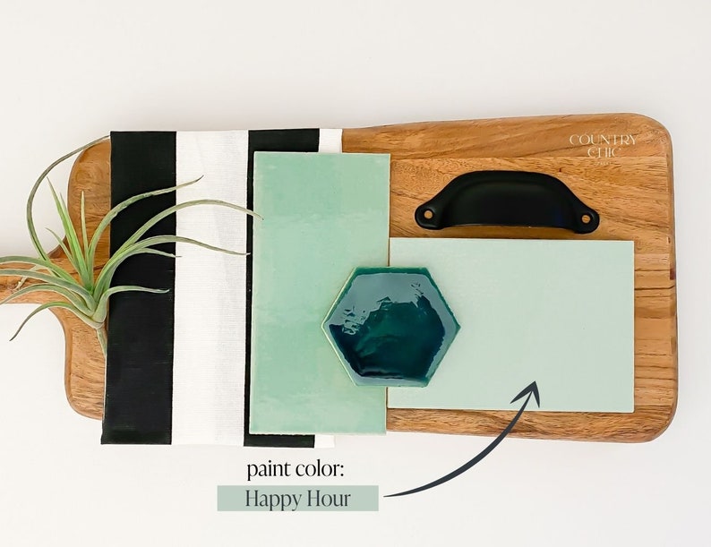 May include: A wooden cutting board with a black handle, a green and black striped fabric, and a green paint swatch labeled "Happy Hour".