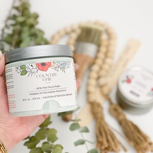 May include: A jar of Country Chic paint in a light green color with a floral design on the label. The label reads "All-In-One Decor Paint" and "Peinture De Decoration Tout En Un". The jar is 16 fl oz or 475 ml.