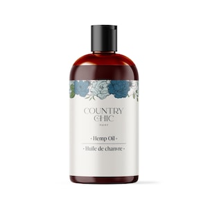 以下が含まれることがあります： 白いラベルに「COUNTRY CHIC PAINT」と「Hemp Oil. Huile de chanvre.」と書かれた茶色のガラス瓶。ラベルには青と緑の花の入った花柄のデザインが施されています。