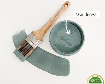 May include: A small jar of green paint with a paintbrush and a white background. The paint is labeled "Wanderess" and has a green "Green Wise Gold" certification label.