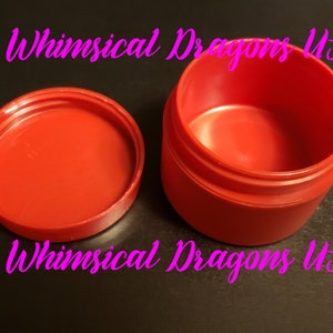 May include: A red plastic container with a lid. The container is empty and the lid is off. The container is labeled "Whimsical Dragons US".