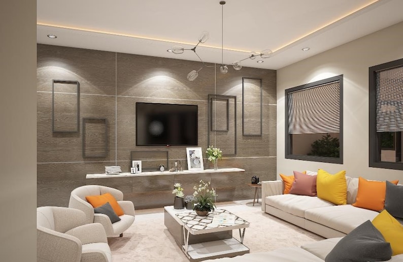 May include: A living room with a white couch and two armchairs. The couch has several throw pillows in shades of orange, yellow, and pink. There is a coffee table in the center of the room with a patterned top. The wall behind the couch is a light brown with a flat screen TV and several framed pictures.