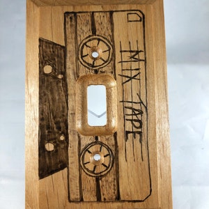 May include: A wooden light switch cover with a woodburned design of a cassette tape with the text "Mix Tape".