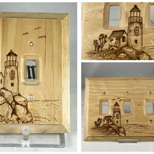May include: A wooden light switch cover with a woodburned design of a lighthouse on a rocky shore. The cover has a single switch opening and is made of light-colored wood.