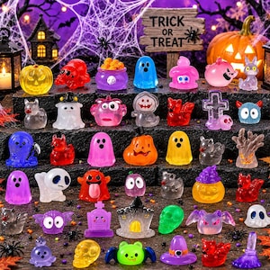 Könnte beinhalten: Eine Sammlung von Miniatur-Halloween-Figuren aus durchscheinendem Material, darunter Geister, Kürbisse, Totenköpfe, Grabsteine und Fledermäuse in verschiedenen Farben. Die Figuren stehen auf Stufen vor einem Schild mit TRICK OR TREAT.