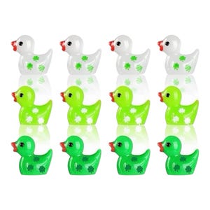 Puede incluir: Ocho pequeñas figuras de pato. Los patos son blancos, verde claro y verde con picos rojos y ojos negros. Cada pato tiene un patrón de trébol en su cuerpo. Los patos están dispuestos en tres filas.