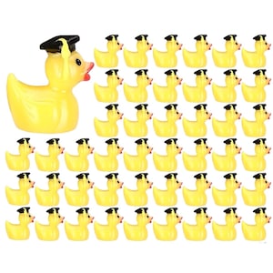 Puede incluir: Un grupo de patitos de goma amarillos, uno con un birrete negro. Los patos tienen picos naranjas y ojos negros. La imagen es una vista superior de los patos dispuestos en filas sobre un fondo blanco.