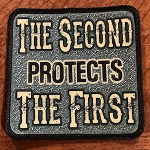 May include: A gray patch with black stitching and white text that reads "The Second Protects The First".