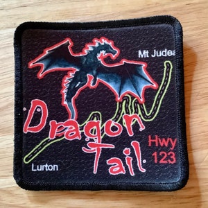 May include: Black and red embroidered patch with a dragon design. The patch says "Dragon Tail" and "Hwy 123" with the text "Mt Juder" and "Lurton" at the top and bottom of the patch.