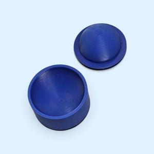 May include: A small, round, deep blue container with a separate matching lid. The lid is dome-shaped, while the base is cylindrical with a hollow interior. Both pieces feature a smooth, solid blue finish and a simple, functional design.
