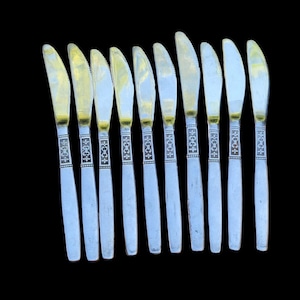 May include: A set of ten silver butter knives with gold accents and black lettering that reads "18/8 + 18/0".
