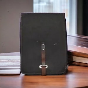 May include: A black leather camera case with a silver metal strap and buckle.