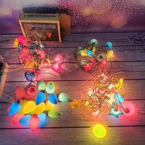May include: Assortment of colorful Christmas lights with a variety of shapes and designs. The lights are strung together and ready to be hung on a Christmas tree or around the house. The lights are a mix of red, green, blue, yellow, and orange.