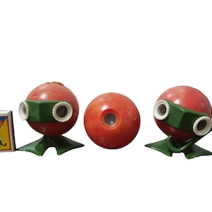 May include: Three red plastic toy cameras with green lenses and a green base. The cameras are arranged in a row on a white background.