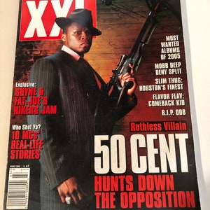 May include: A magazine cover featuring a photo of 50 Cent holding a crossbow. The cover text reads "Ruthless Villain 50 Cent Hunts Down The Opposition". The magazine is titled "XXL" and the issue is March 2005.