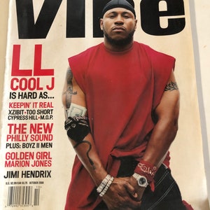 May include: A magazine cover featuring LL Cool J in a red shirt and black bandana. The magazine is titled "Vibe" and the cover text reads "Backstage Pass: The Hard Knock Life Tour Goes Hollywood".