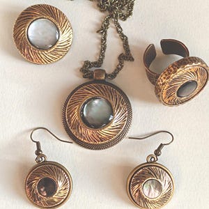 Parure di gioielli vintage realizzata con bottoni antichi in madreperla iridescente, anni '50-'70: collana, collana lunga, anello regolabile, spilla, orecchini, bronzo antico