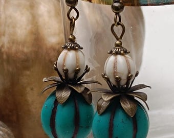Könnte beinhalten: Türkise und weiße gestreifte Glasperlenohrringe mit bronzefarbenen Akzenten. Die Ohrringe haben ein florales Design und einen Hakenverschluss.