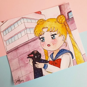 May include: Watercolor illustration of a Sailor Moon character holding a black creature with white dots. The character has blonde hair in buns and wears a sailor uniform with a red bow. The background shows a building.