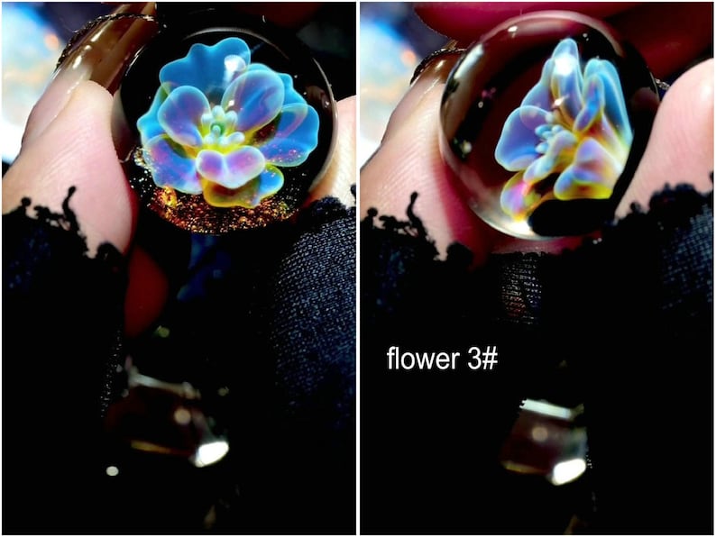 May include: A clear glass pendant with a blue, yellow, and purple flower design. The pendant is round and has a silver-colored bail. The text "flower 3#" is visible in the image.