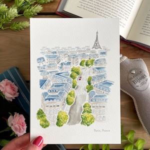 K&ouml;nnte beinhalten: Ein Aquarellgem&auml;lde einer Stra&szlig;enszene in Paris, Frankreich. Das Gem&auml;lde zeigt eine Stra&szlig;e, die von Geb&auml;uden, B&auml;umen und einem roten Auto ges&auml;umt ist. Der Eiffelturm ist in der Ferne sichtbar. Das Gem&auml;lde ist mit "Paris, Frankreich" signiert.