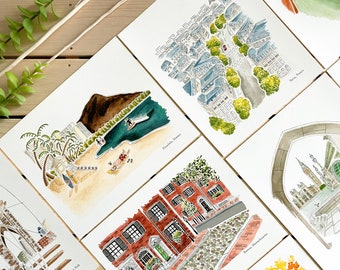 Puede incluir: Conjunto de ilustraciones de acuarela de diferentes ciudades, incluyendo Honolulu, Hawái, Boston, Massachusetts y la ciudad de Nueva York. Cada ilustración está enmarcada con un borde blanco y presenta un estilo arquitectónico único.