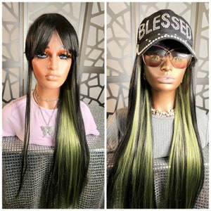 May include: Two mannequin heads display long black wigs with green highlights. One mannequin wears a pink shirt and a butterfly pendant necklace. The other wears a black baseball cap with the word "BLESSED" in rhinestones and large sunglasses.
