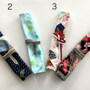May include: Four different fabric-wrapped chopsticks with various patterns. The chopsticks are tied with a ribbon and numbered 1 through 4.