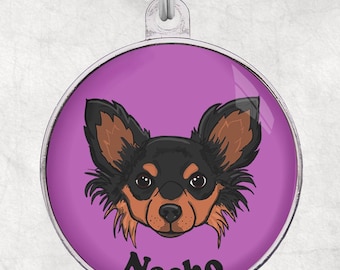 May include: A purple round dog tag with a cartoon chihuahua with brown ears and black fur. The dog's name "Nacho" is written in black letters below the dog's face.