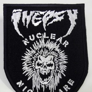 Op de afbeelding: Zwarte patch met wit geborduurde tekst en een schedelontwerp. De patch leest "WEPSY NUCLEAR NIGHTMARE" in een gotisch lettertype. De schedel is omgeven door stralende lijnen, waardoor hij een vurig uiterlijk krijgt. De patch heeft een gebogen onderrand.