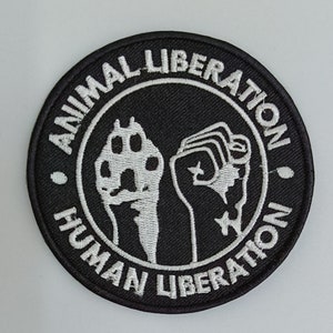 May include: Black and white embroidered patch with the text "Animal Liberation Human Liberation" in a circle around a raised fist and a paw print.