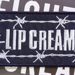 May include: Black embroidered patch with white barbed wire and the text "LIPCREAM" in white.