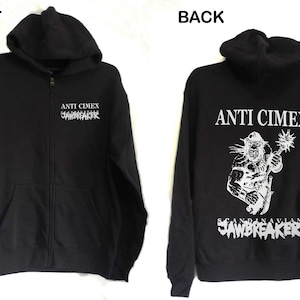 May include: Black zip-up hoodie with a white graphic print on the front that says "ANTI CIMEX SCANDINAVIAN SAWBREAKER". The back of the hoodie has a white graphic print of a person holding a weapon with the text "ANTI CIMEX SCANDINAVIAN SAWBREAKER".