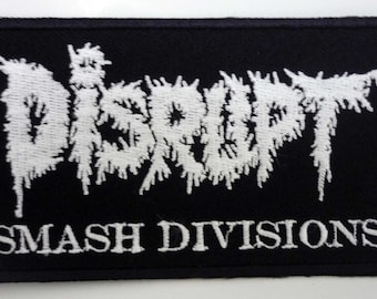 May include: Black rectangular patch featuring white embroidered text. The word "DISRUPT" is in a distressed font above "SMASH DIVISIONS". Suitable for application on clothing or bags.