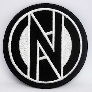 Könnte beinhalten: Schwarz-weiß gestickter Aufnäher mit einem stilisierten Buchstaben "N" in einem Kreis.