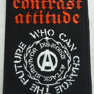 May include: Black and white embroidered patch with the text "Contrast Attitude" in red lettering at the top. The centre of the patch features a white anarchy symbol surrounded by a wreath with the text "Who Can Change The Future Without Disobeying The Rules".