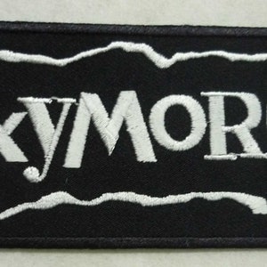 Op de afbeelding: Zwart-witte geborduurde patch met het woord "OXYMORON" in een witte, onregelmatig omrande rechthoek.