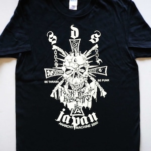 Peut inclure: T-shirt noir avec un motif blanc représentant un crâne avec des pointes et des chaînes, une croix et le texte "Be Thrash" et "Be Punk". Le texte "Japan Anarchy Machine 2000" est situé sous le motif.