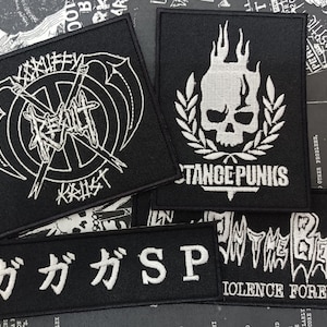 Könnte beinhalten: Fünf schwarze gestickte Patches mit weißen Buchstaben. Die Patches zeigen Bandnamen und Logos, darunter "Resist", "Distant Punks", "In The Beach" und "ガガガSP".
