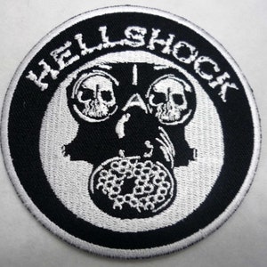 May include: A black and white embroidered patch with the text "HELLSHOCK" in a circle around a white gas mask with two skulls.