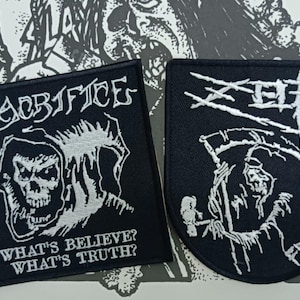 May include: Two black embroidered patches with white thread designs. The square patch features a hooded skull and the text "SACRIFICE" and "WHAT'S BELIEVE? WHAT'S TRUTH?". The shield-shaped patch features a grim reaper and the text "ZEF" and "FROM HELL".