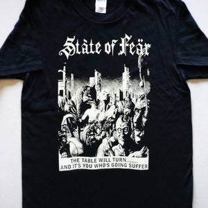 May include: Black t-shirt with a white graphic print of a band called "State of Fear". The graphic features a chaotic scene of people in a city with the text "The table will turn... and it's you who's going suffer".