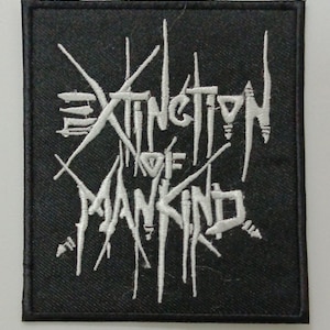 Puede incluir: Parche bordado en blanco y negro con el texto "Extinction of Mankind" en una fuente estilizada.