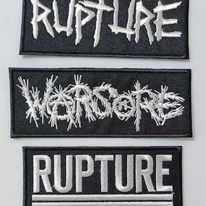 May include: Three black fabric patches with white embroidered text. The top patch says "RUPTURE" in a jagged font. The middle patch says "WARSORNE" in a jagged font. The bottom patch says "RUPTURE" in a block font with two white lines below the text.