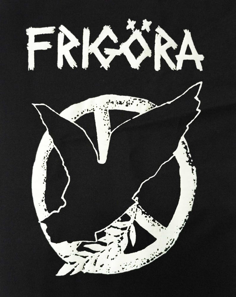 May include: Black graphic featuring the word "FRIG&Ouml;RA" in white, stylized, distressed lettering above a white peace symbol. Inside the peace symbol is a white dove with outstretched wings and an olive branch.