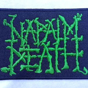 Puede incluir: Parche bordado verde con las palabras "NAPALM DEATH" sobre un fondo azul oscuro.