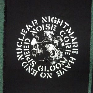 May include: Black square patch with white text and a skull graphic. The text reads "NUCLEAR NOISE NIGHTMARE CORE HAVE SEEN BLOOM ON FLAME". The patch has a raw edge.