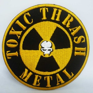 May include: Black and yellow embroidered patch with a skull and crossbones inside a yellow radiation symbol. The text "TOXIC THRASH METAL" surrounds the symbol.