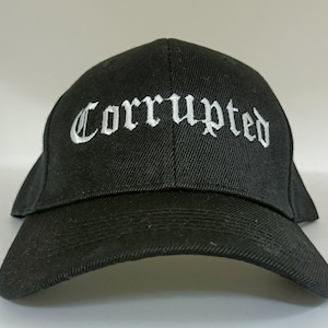 Puede incluir: Gorra de béisbol negra con texto bordado en blanco que dice "Corrupted" en letra inglesa antigua.